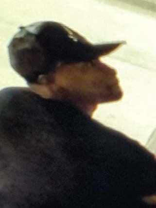 Photo of theft suspect with black ball cap, black shirt and black audio headset